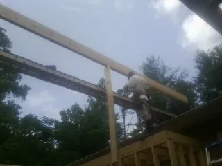 Carpenter setting a ridge beam over a new addition frame — Ice Dam Removal by Roofing Brothers in Anna Maria