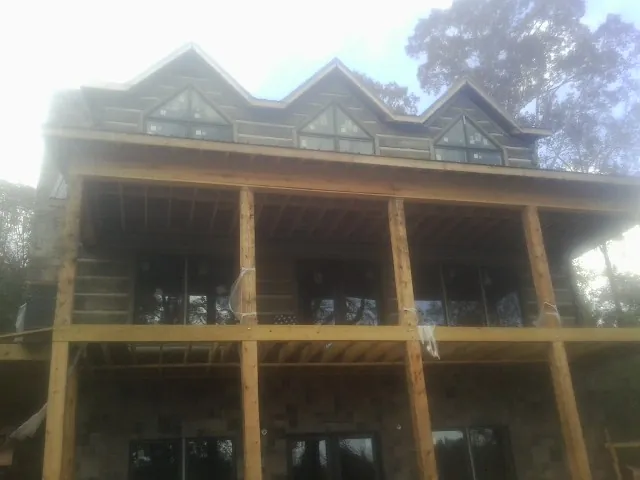 Dormers and porch framing on a large log home under construction — Roof Coating work by our crew in Anna Maria