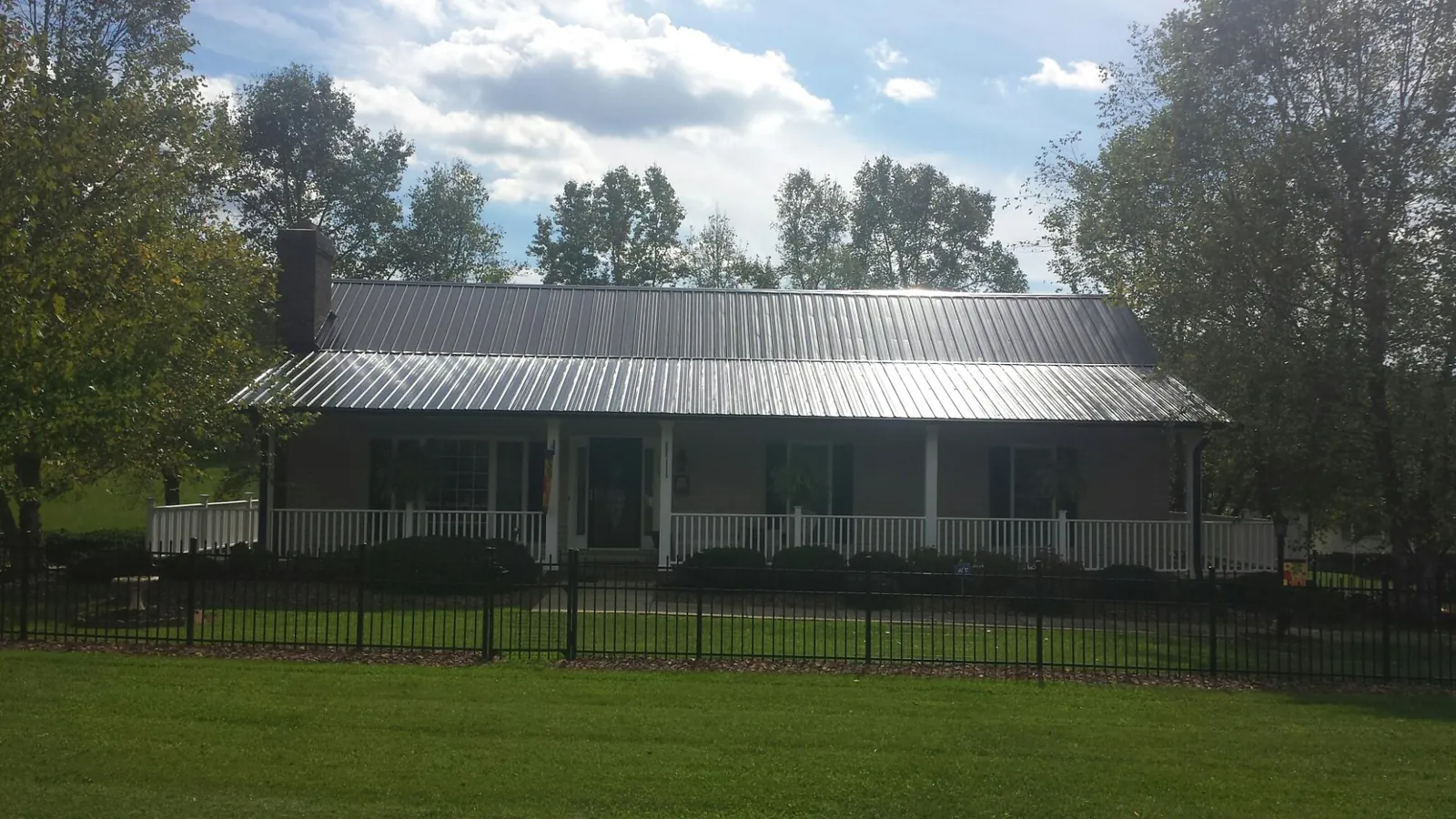 Gray metal roof on a brick ranch with a full width front porch — Gutter Guard Installation work by our crew in Anna Maria