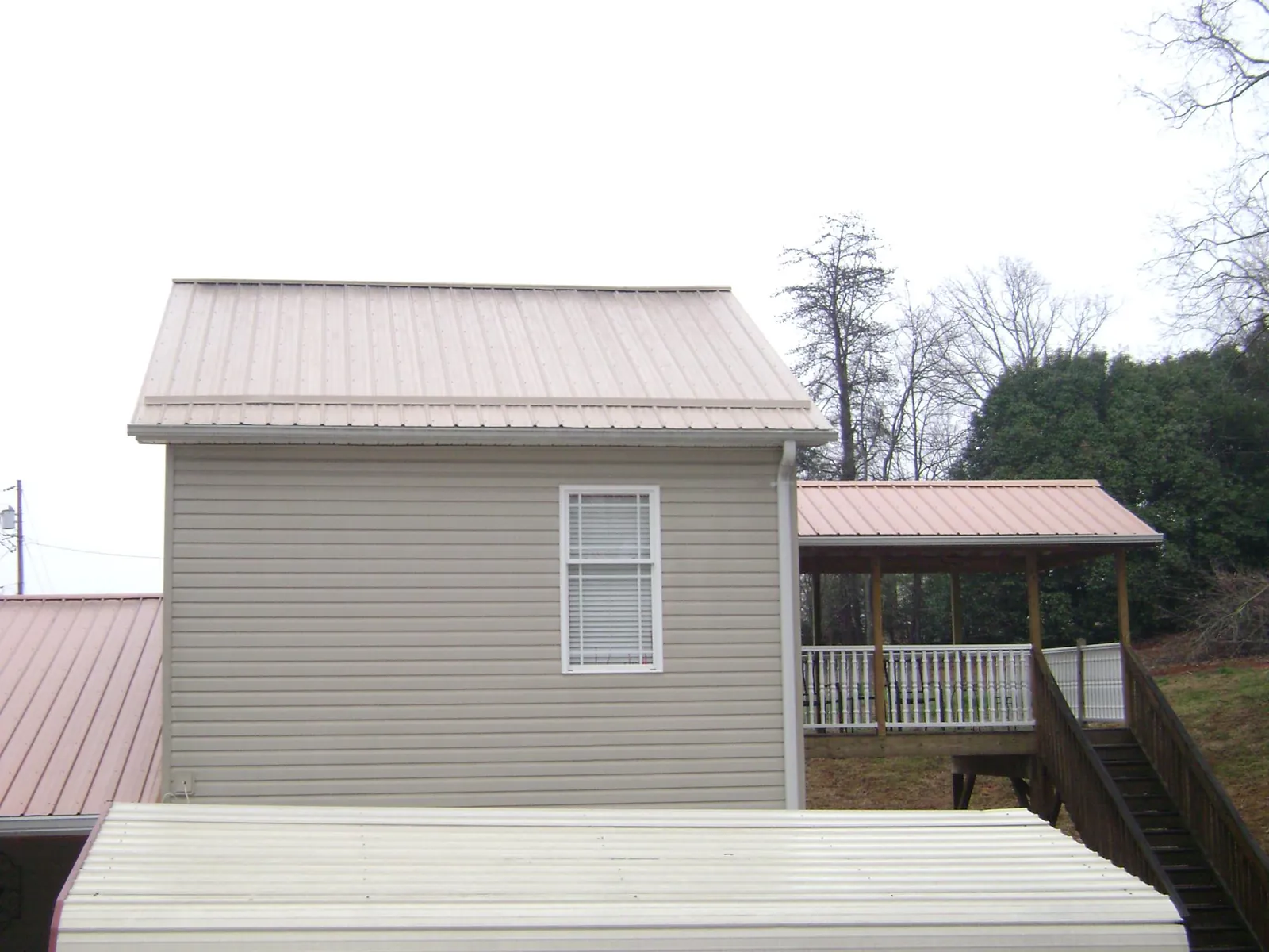 Tan metal roofs on a two story addition and attached porch, from a Roof Replacement job in Anna Maria