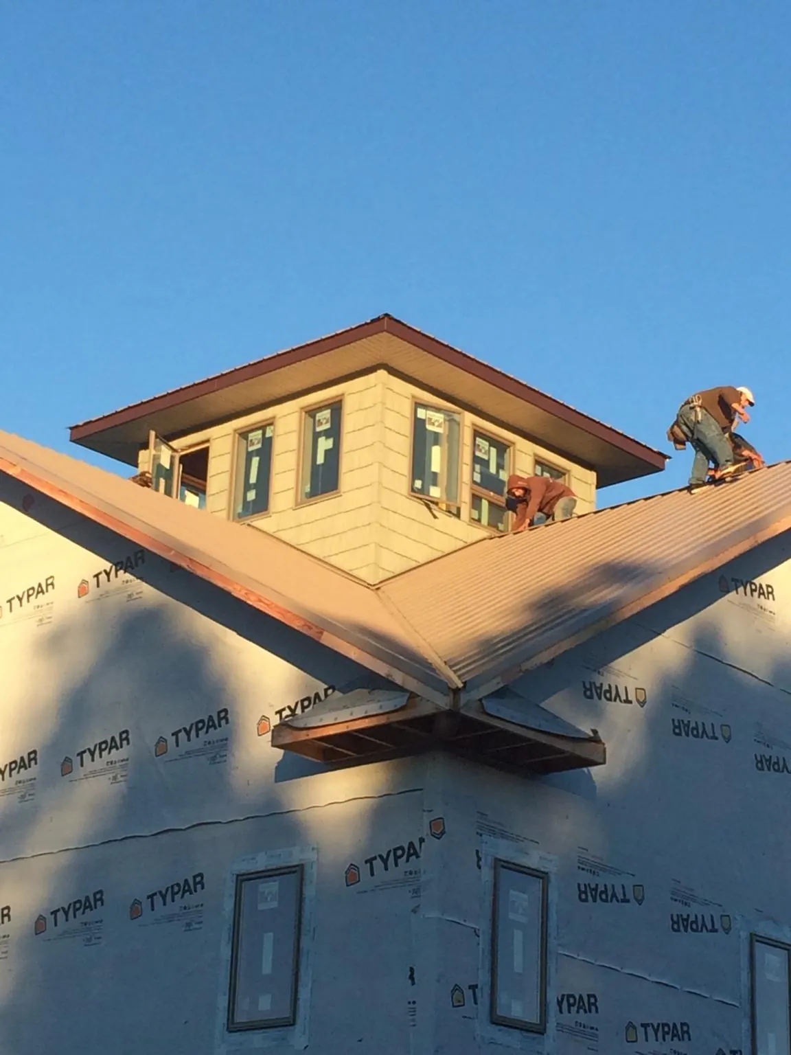 Roofers working around a rooftop cupola on a new metal roof at sunset — Roof Waterproofing in Anna Maria by Roofing Brothers